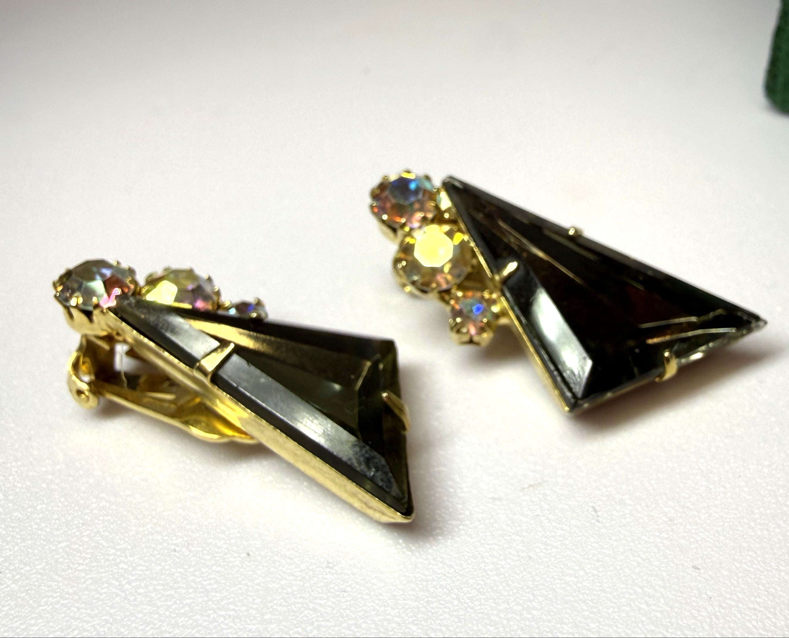 Pair of gold and black triangle-shaped earrings on a white surface.